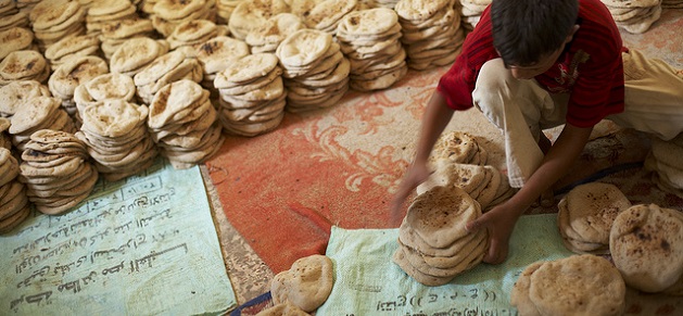 A boy divides cooled baladi bread into twenty loaf stacks, (the daily ration) at the El Beayrat bakery outside of Luxor, Egypt. Over three thousand pieces of bread are produced at this bakery each morning. In Egypt, flour is fortified with essential micronutrients to help combat widespread anemia. Introduced in 2008 with support from United Nations World Food Program, Global Alliance for Improved Nutrition (GAIN), and the Egyptian Ministry of Social Solidarity, the program adds iron and folic acid to baladi bread - the staple food of Egyptians.