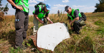 A Dutch and an Australian Police officer investigate the scene of the MH17 crash. Photo Credit: Wikimedia Commons (Dutch Department of Defence) Creative Commons.