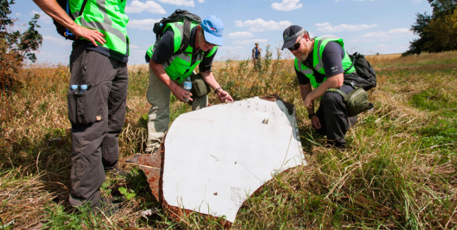 A Dutch and an Australian Police officer investigate the scene of the MH17 crash. Photo Credit: Wikimedia Commons (Dutch Department of Defence) Creative Commons.