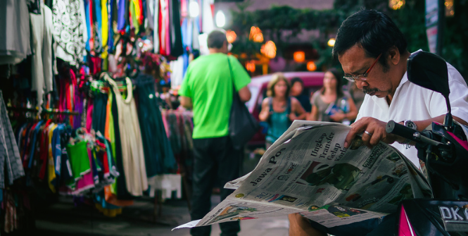 A Man reads an Indonesian Newspaper on the street. Photo Credit: Flickr (Just Call Me Mo) Creative Commons.