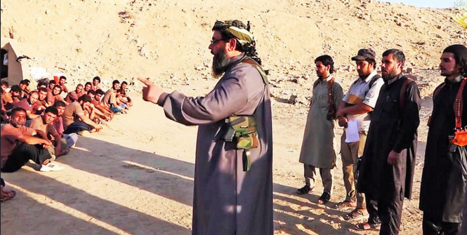 Sheikh armed with knife & pistol teaches with outstretched index recruits in IS-Boot-Camp. Screen shot of IS traning video provided by quapan (Flickr). Creative Commons.