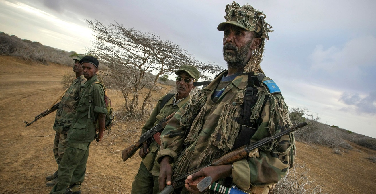 Soldiers of the Somali National Army watch from the roadside as a convoy carrying troops begins an advance on the Somali port city of Kismayo
