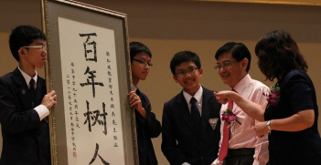 Students presenting a piece of calligraphy to Heng Swee Keat. Source: Wikimedia Commons. 