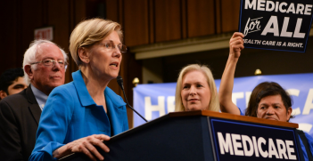 Sen. Elizabeth Warren (D-Mass.) speaks at the introduction of the Medicare for All Act of 2017 on Sept. 13, 2017 as Senator Bernie Sanders looks on.  Source: Senate Democrats https://bit.ly/2PrCT21