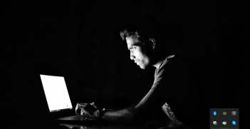 Man sits at a computer in the dark.  Source: https://bit.ly/332qUNG