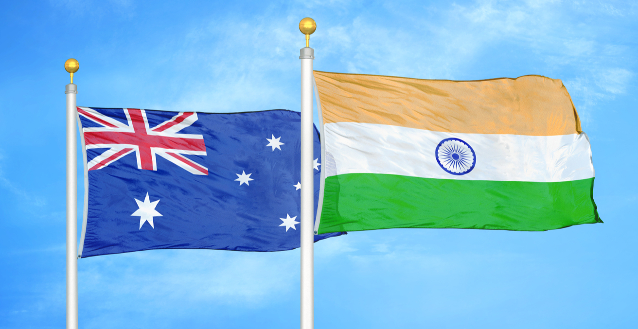 Australian and Indian flags on flagpoles with a blue cloudy sky background. Credit: Alex Shutter/Shutterstock.com