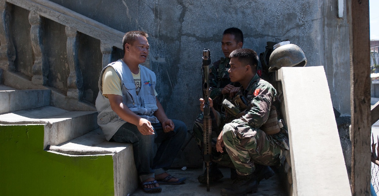 A peacebuilder with Nonviolent Peaceforce talks with two AFP soldiers. Source: Nonviolent Peaceforce https://bit.ly/3fubPcS