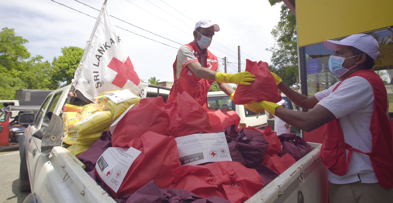ICRC workers wearing masks distribute supplies from a truck. Source: ICRC