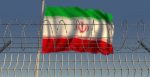 Blurred waving flag of Iran behind barbed wire fence, representing imprisonment. 
Source: Novikov Aleksey, https://shutr.bz/30FD7YG