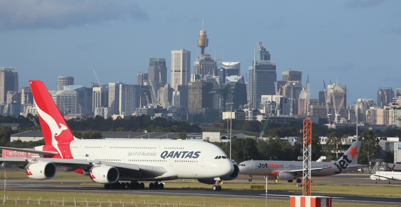 Qantas A380 Taxiing At Sydney Airport With City In Background. Source: Skatebiker https://bit.ly/34pXrik