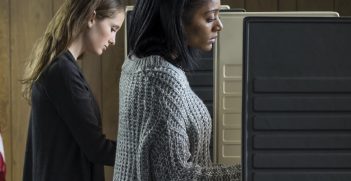 Two young adult women voting in a voting booth. Source: Burlingham/Shutterstock