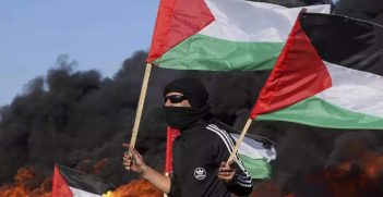 Man holding Palestinian flags in Gaza. Source: Quickspice / https://www.flickr.com/photos/189675325@N04/52706193670